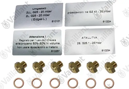 Düsenwechselsatz von Vaillant mit mehreren Düsen und Kupferdichtungen, Anleitungshinweisen in verschiedenen Sprachen auf Metalltafeln.